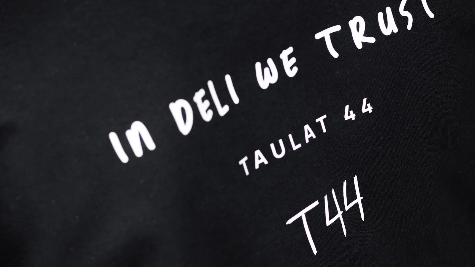 Bolsa negra de T.44 con las palabras In deli we trust